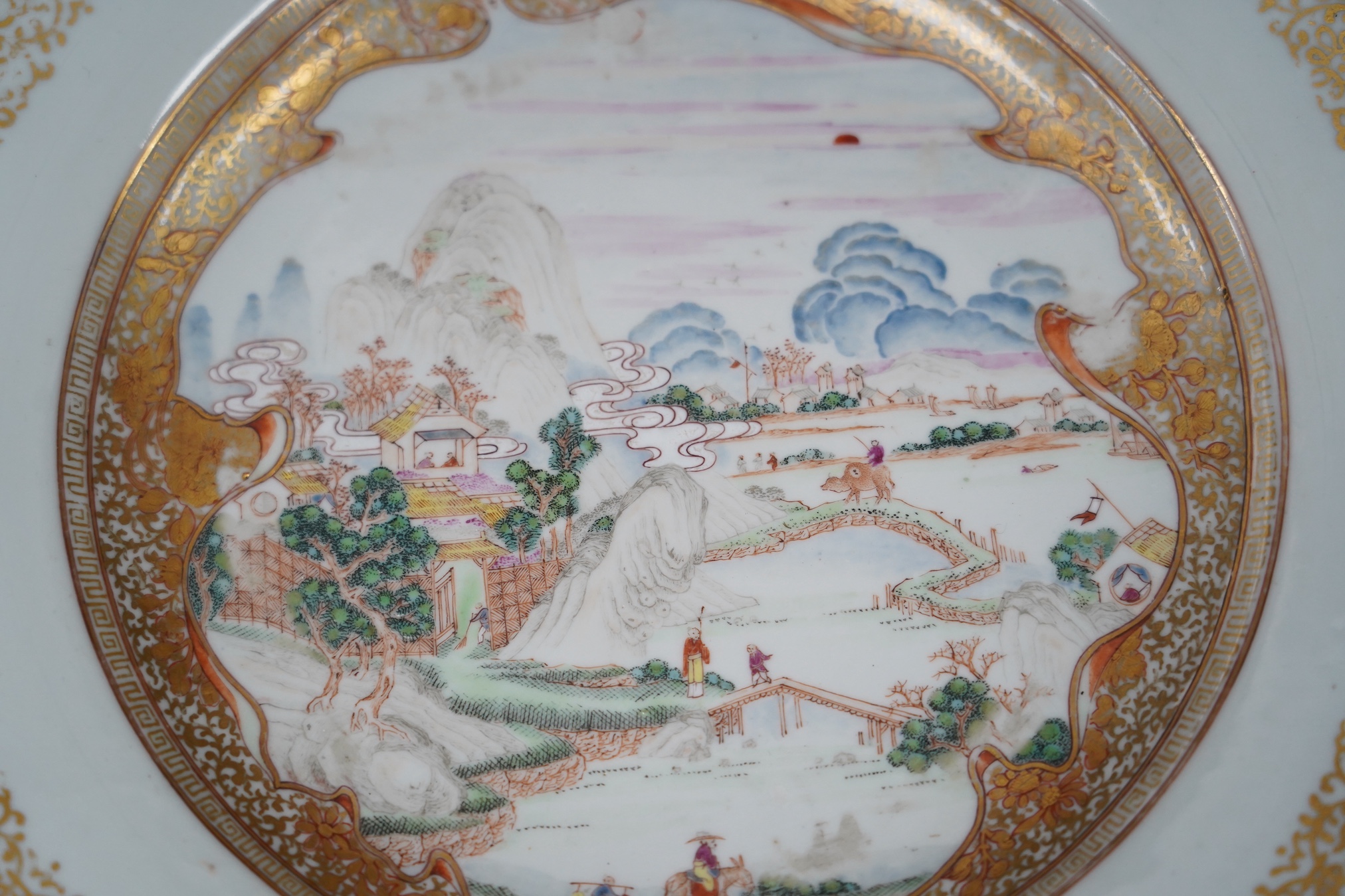 A pair of Chinese famille rose ‘landscape’ plates, Yongzheng-Qianlong period, small edge chip